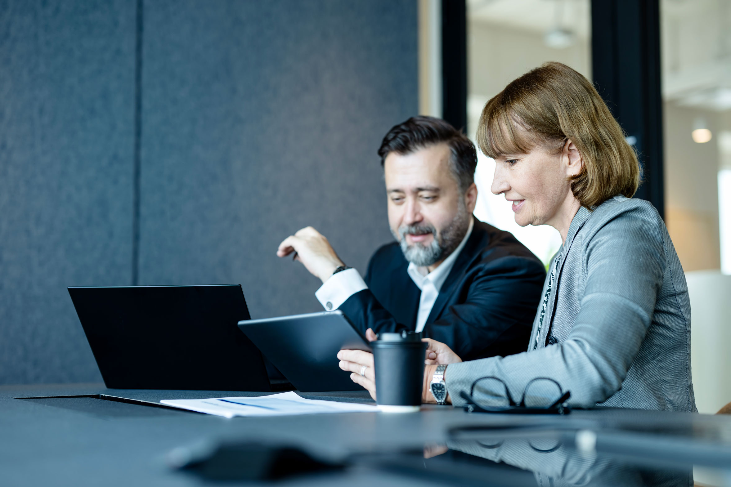 Senior Businesswomen in executive meetings show business vision on a tablet computer with businessmen in a meeting room.