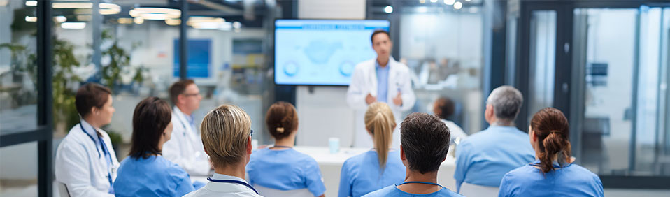 A health professional standing in front of an audience of peers discussing evidence based health.